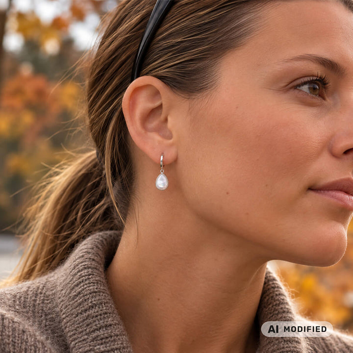 Hopeanvärinen teräskorvarengas pisaranmuotoisella helmiäisriipuksella korvassa